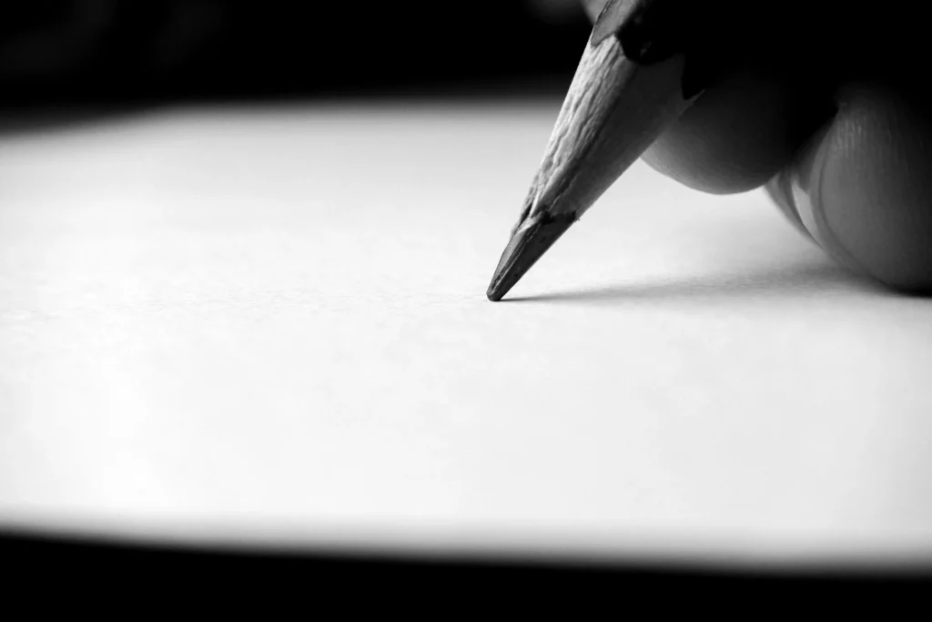 A pencil writing on a blank white card, close up